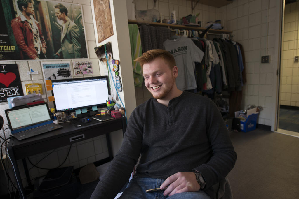 Male student in Mason residence hall with computer screens on desk